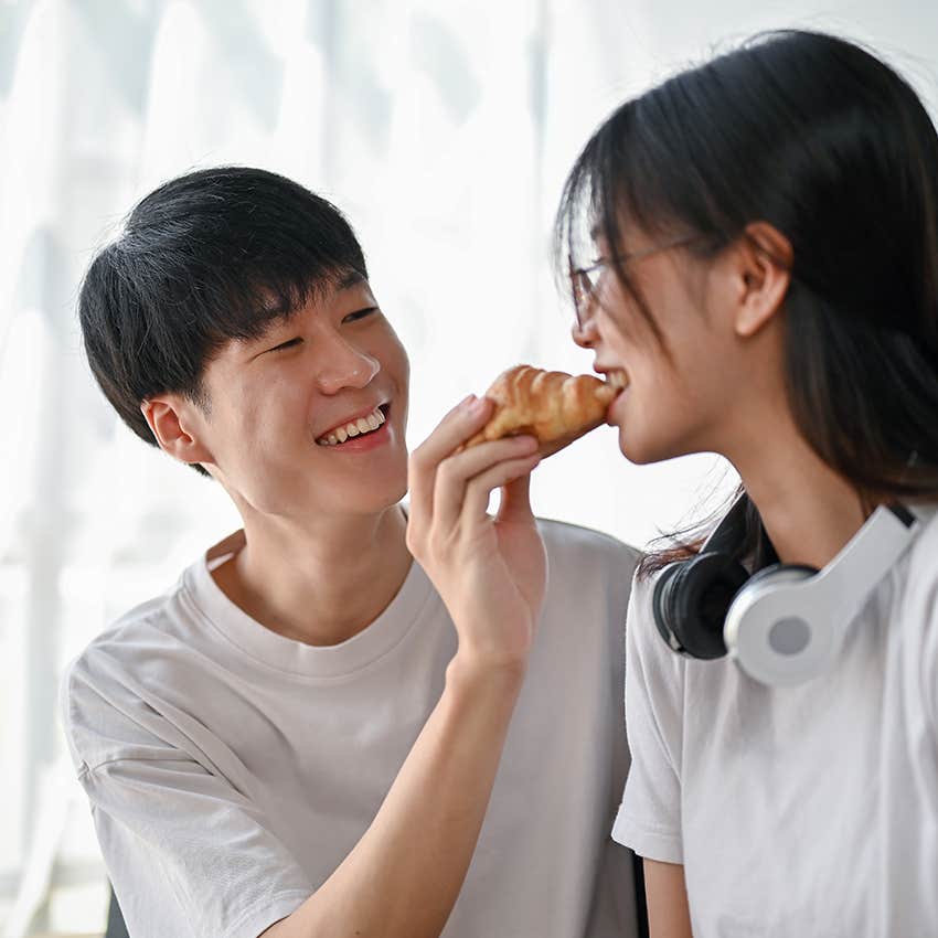 man feeding last bite of croissant to his girlfriend