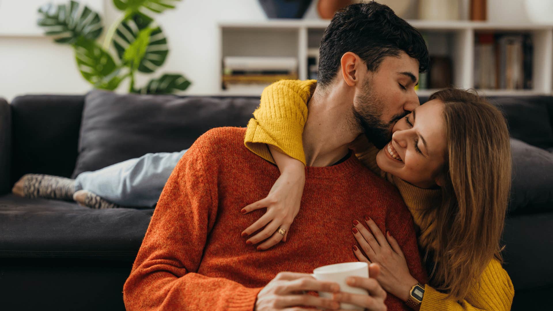 man in red shirt kissing woman on the cheek as he shows more intentional intimacy