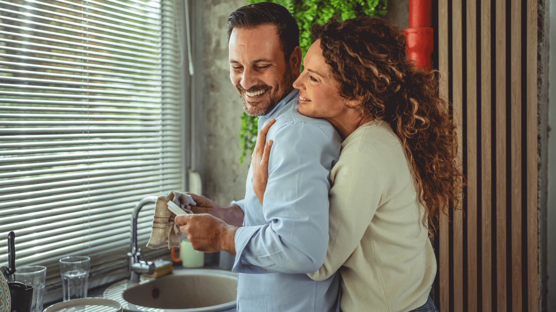woman in green shirt hugging man from behind as they have reduced resentment 