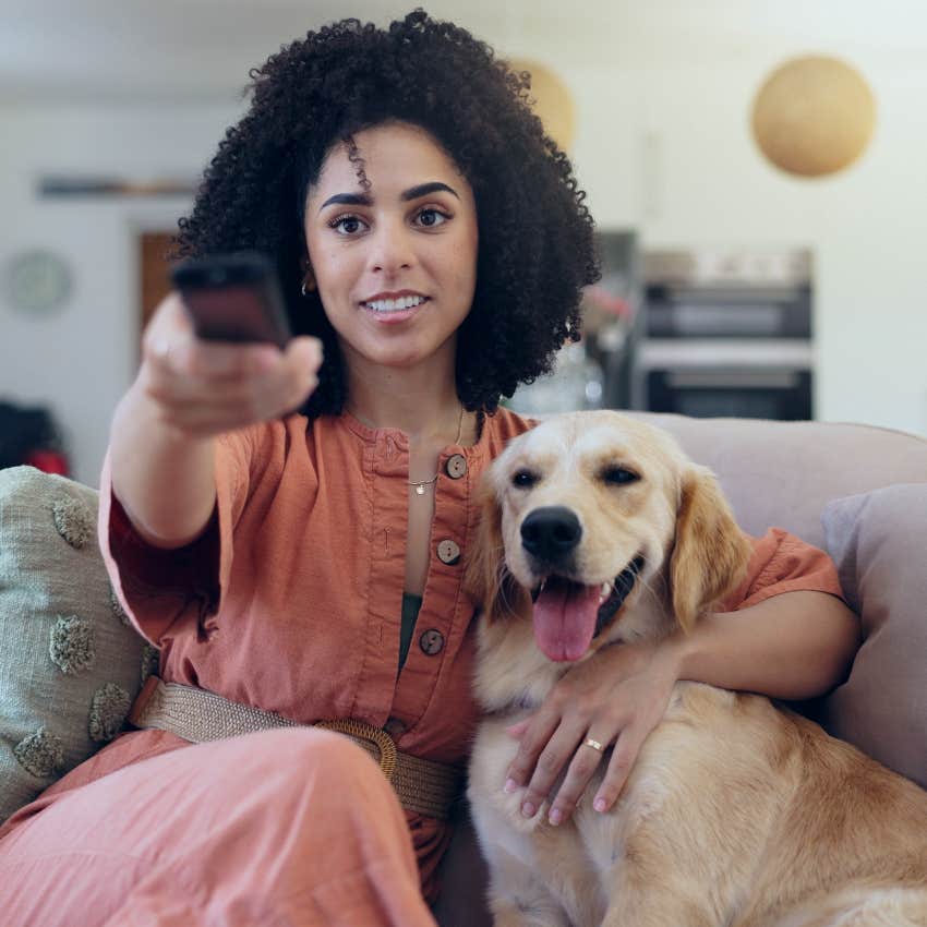 woman watching horror movie with dog on couch 