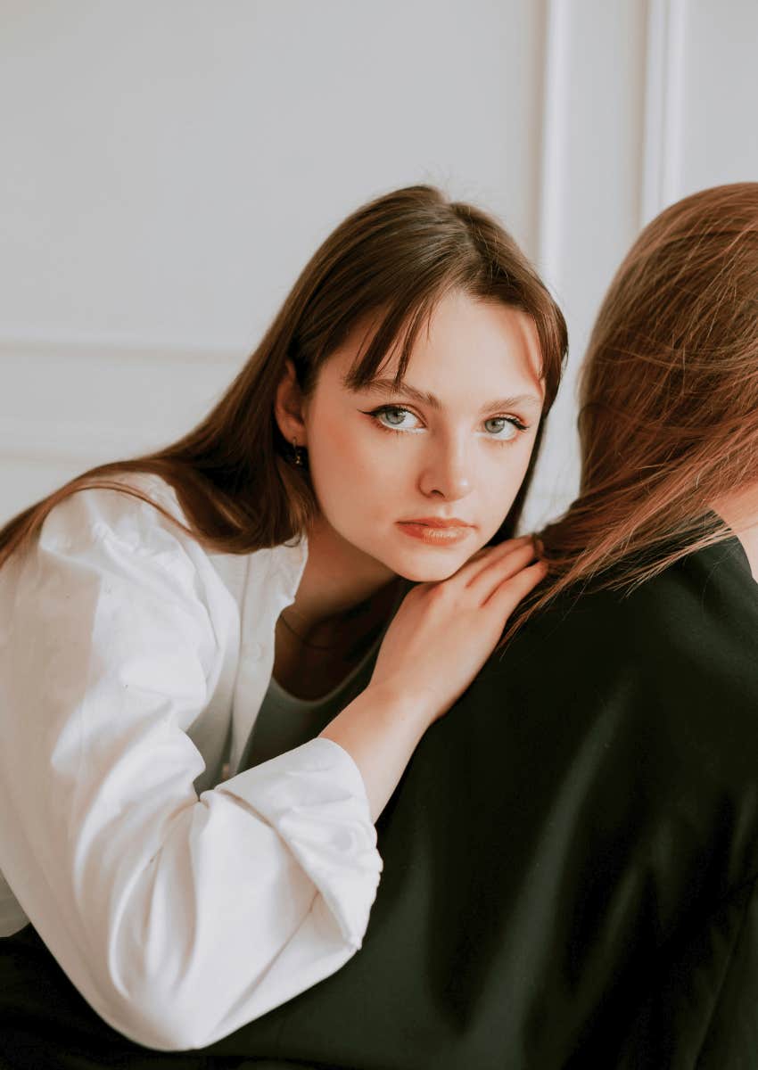 serious female sitting behind toxic friend