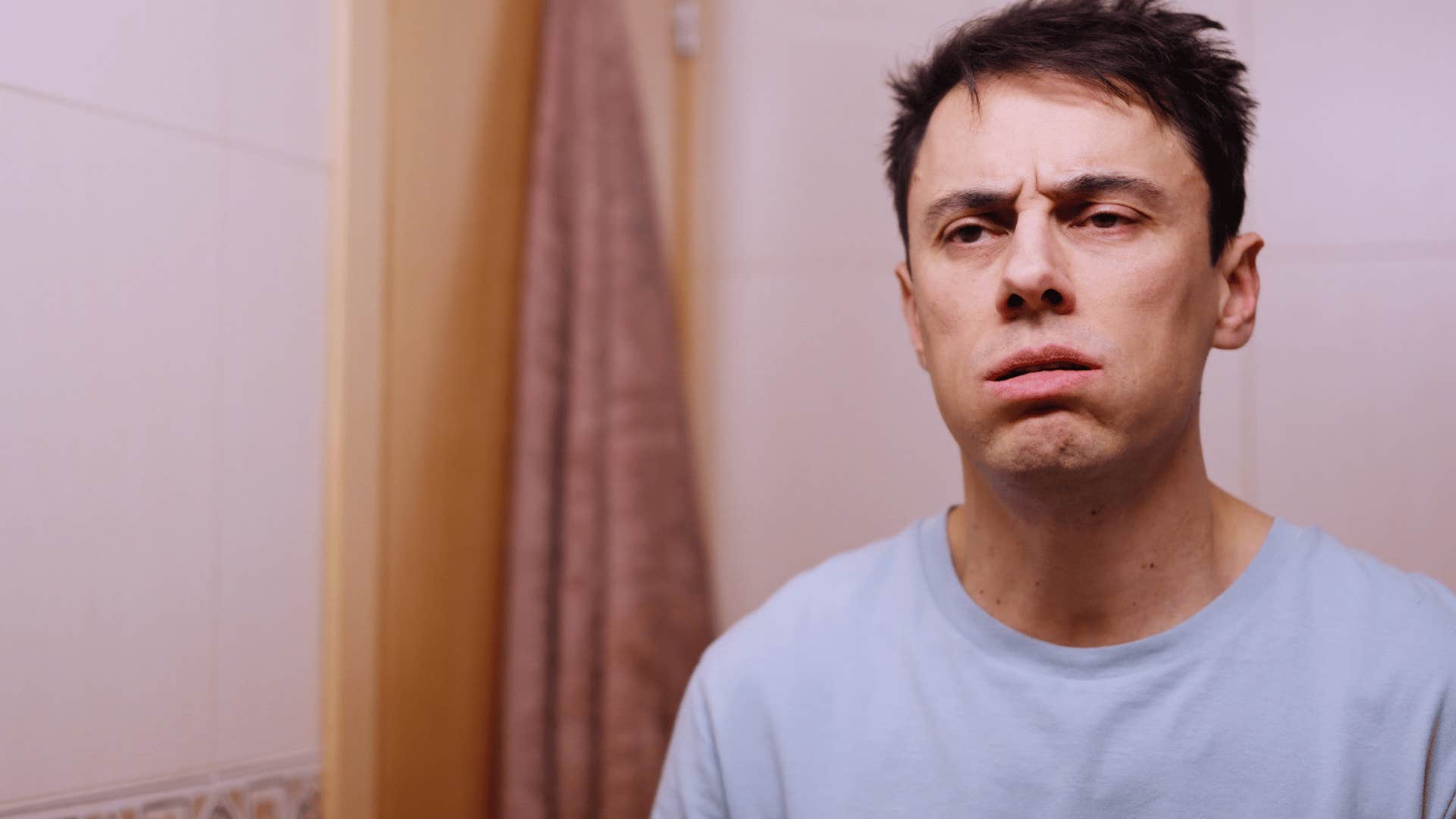 depressed man looking in mirror putting less effort into his appearance
