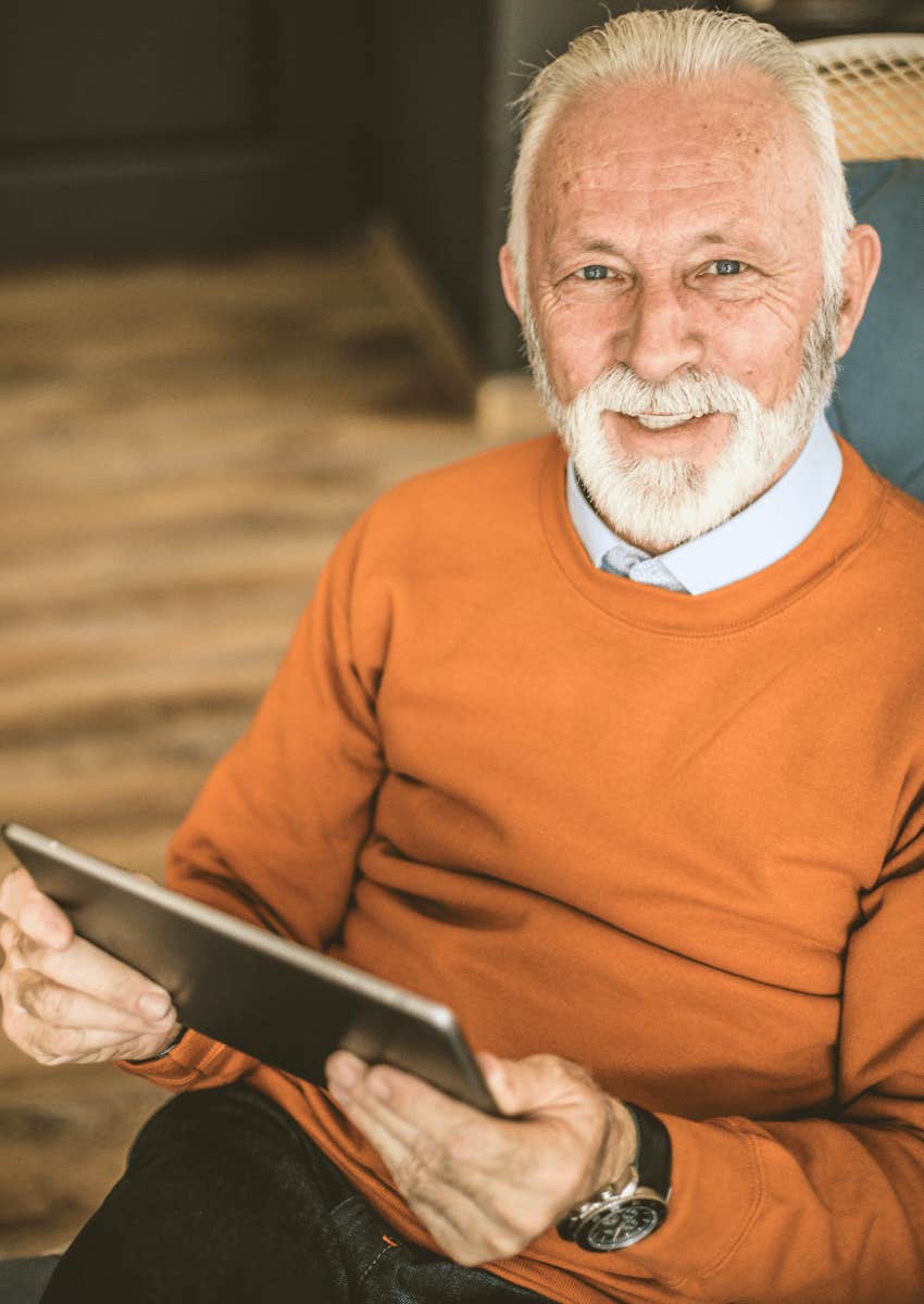 smiling older man in retirement holding a tablet