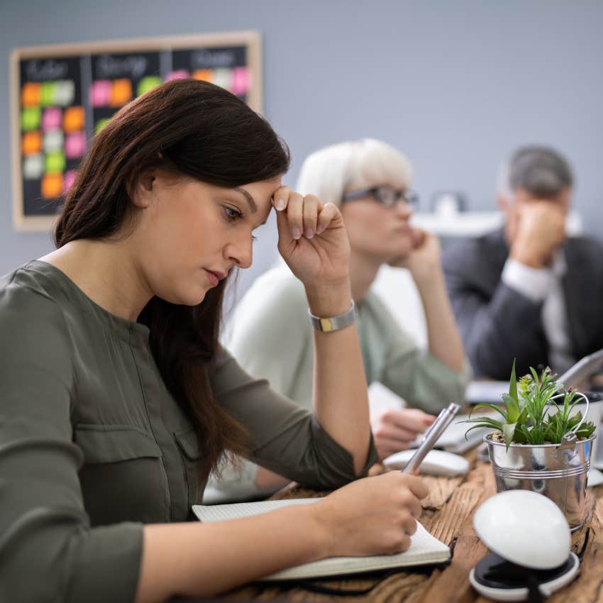 disengaged employee taking notes during work meeting