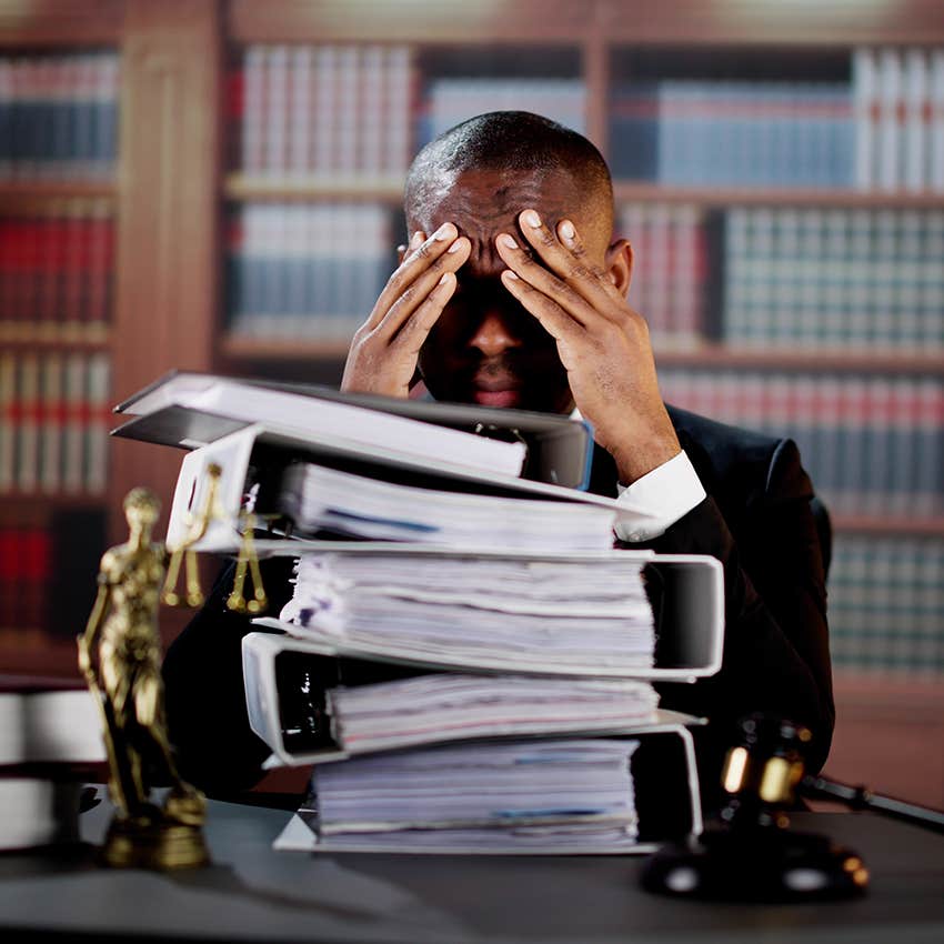 stressed lawyer with piles of paperwork on desk