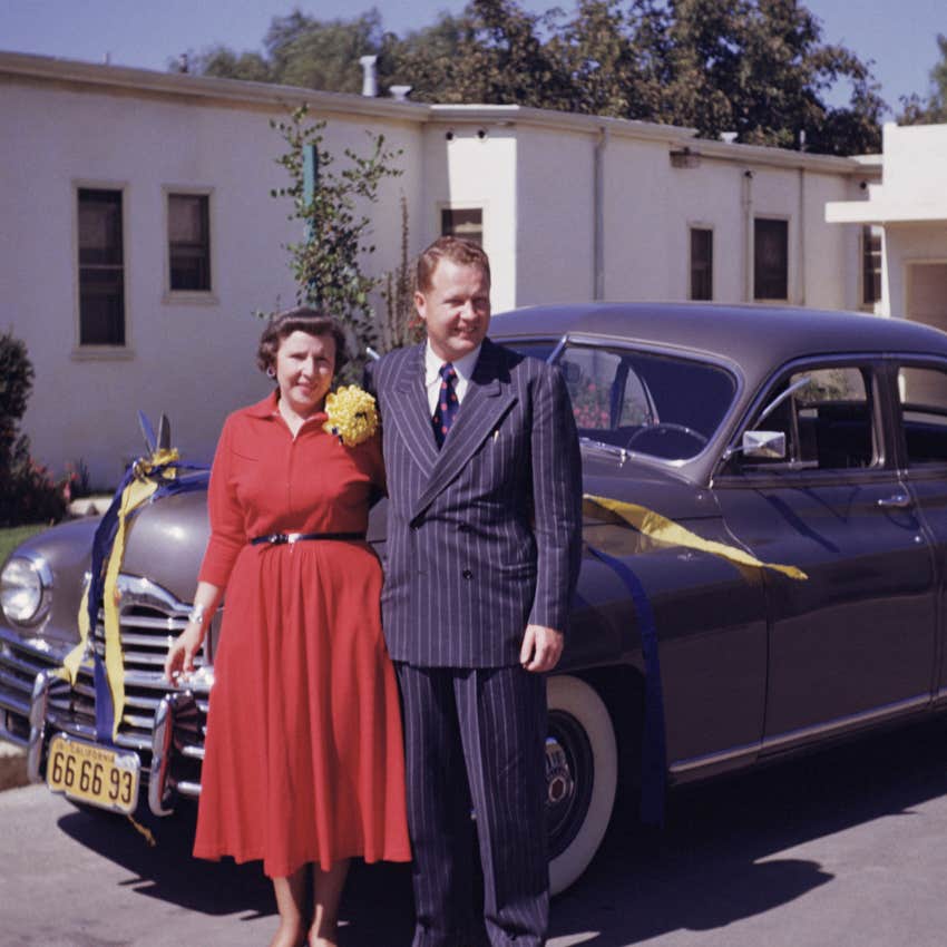 boomer couple standing next to their new car