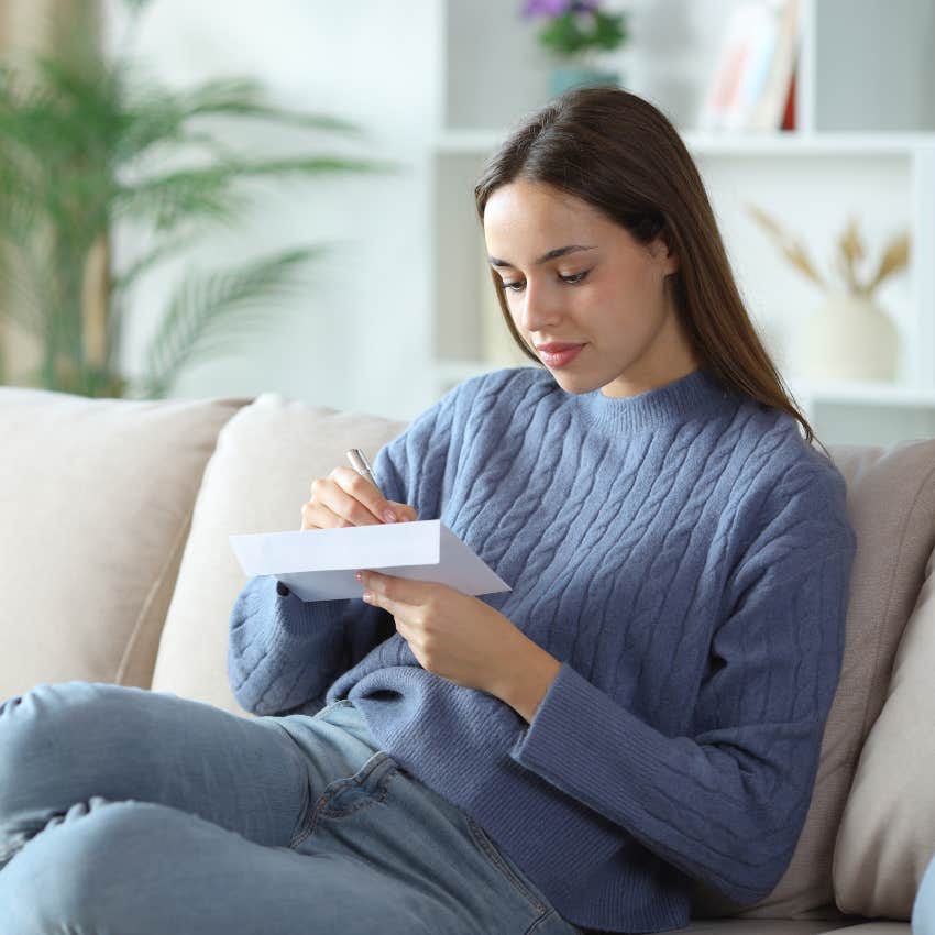 young woman writing on envelope confused by checkbooks