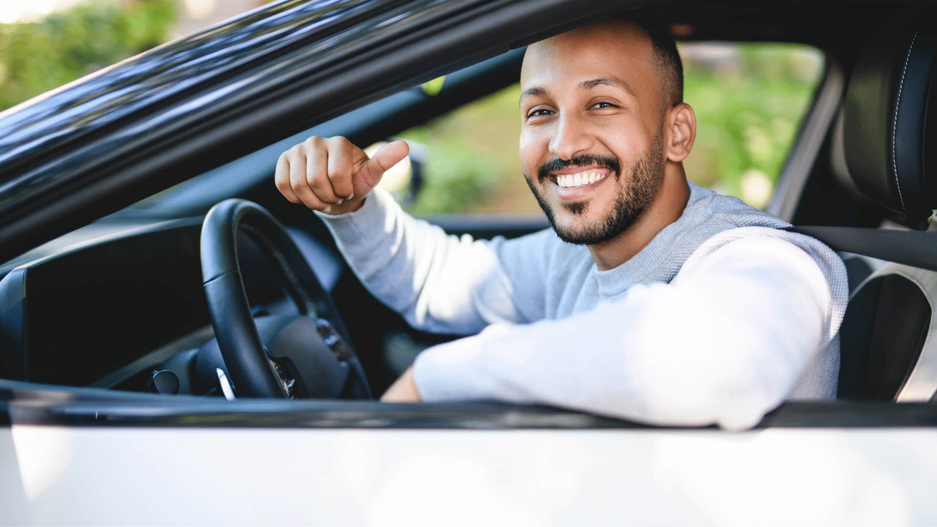 man driving a brand new car looking happy