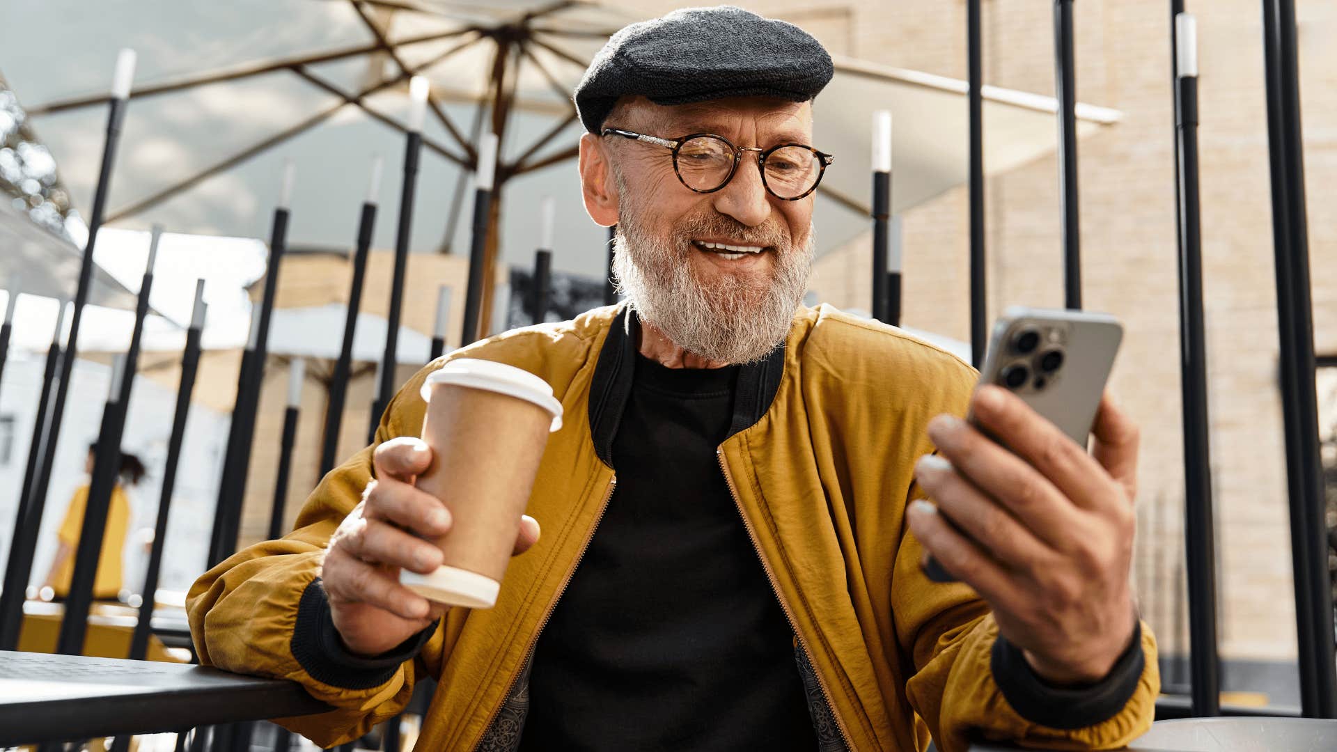retired man enjoying coffee and reading the news on his phone