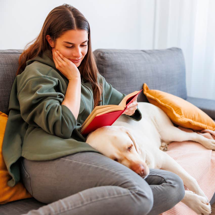 interesting woman sitting on couch reading a book that's outside her comfort zone