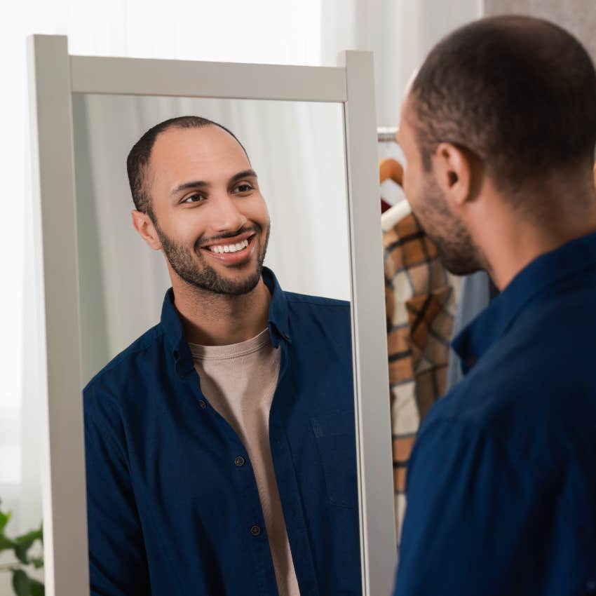 man smiling at himself in mirror feeling comfortable being himself