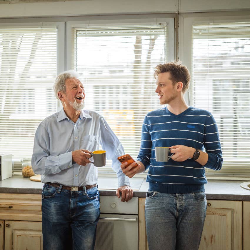 senior father and adult son drinking coffee in kitchen