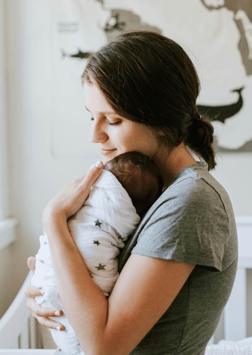 woman hugging newborn baby close to her chest