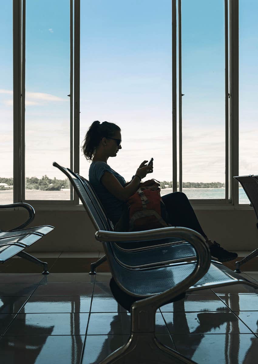 woman sitting alone in a waiting area on her phone