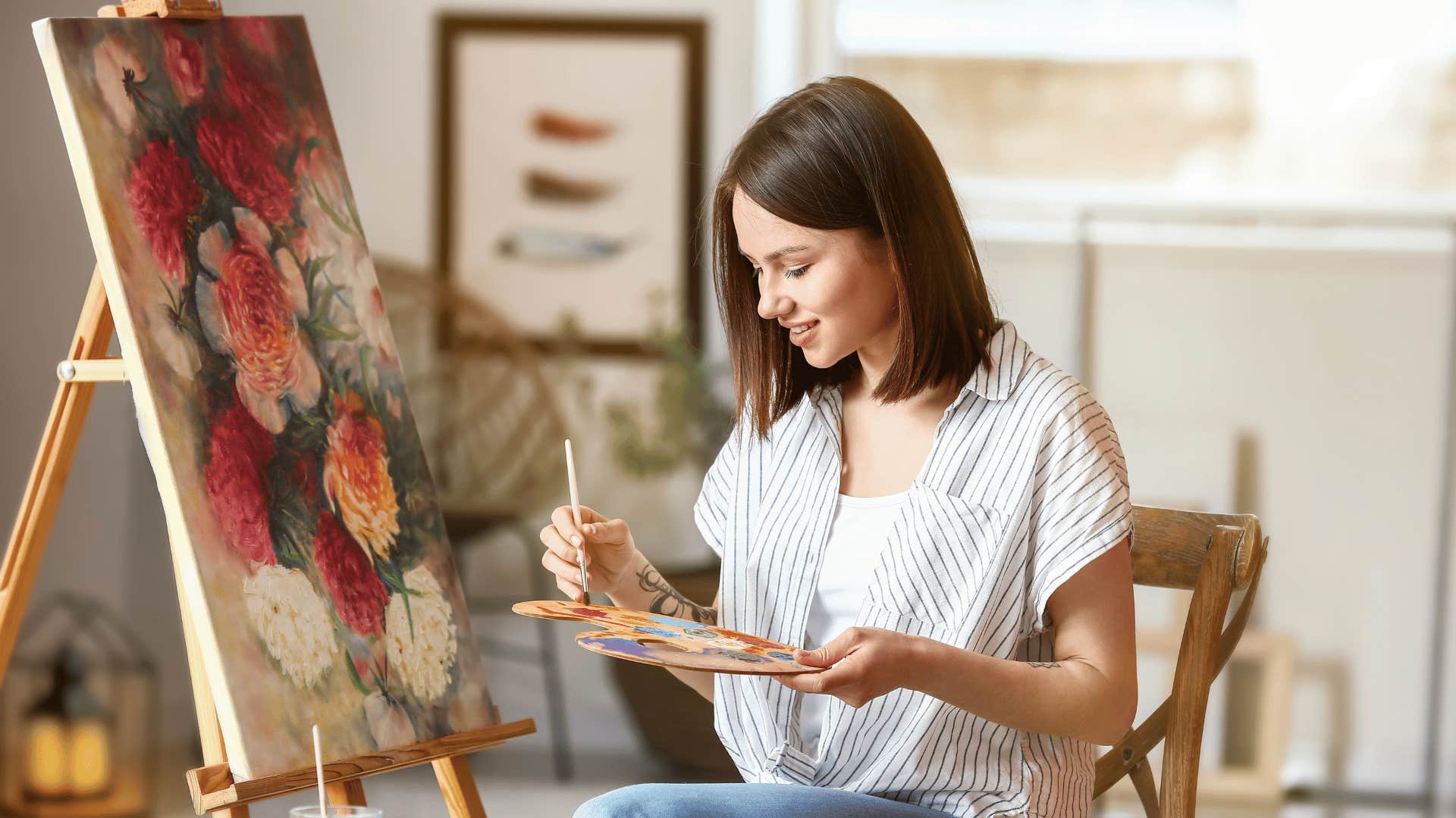 creative woman painting flowers on canvas