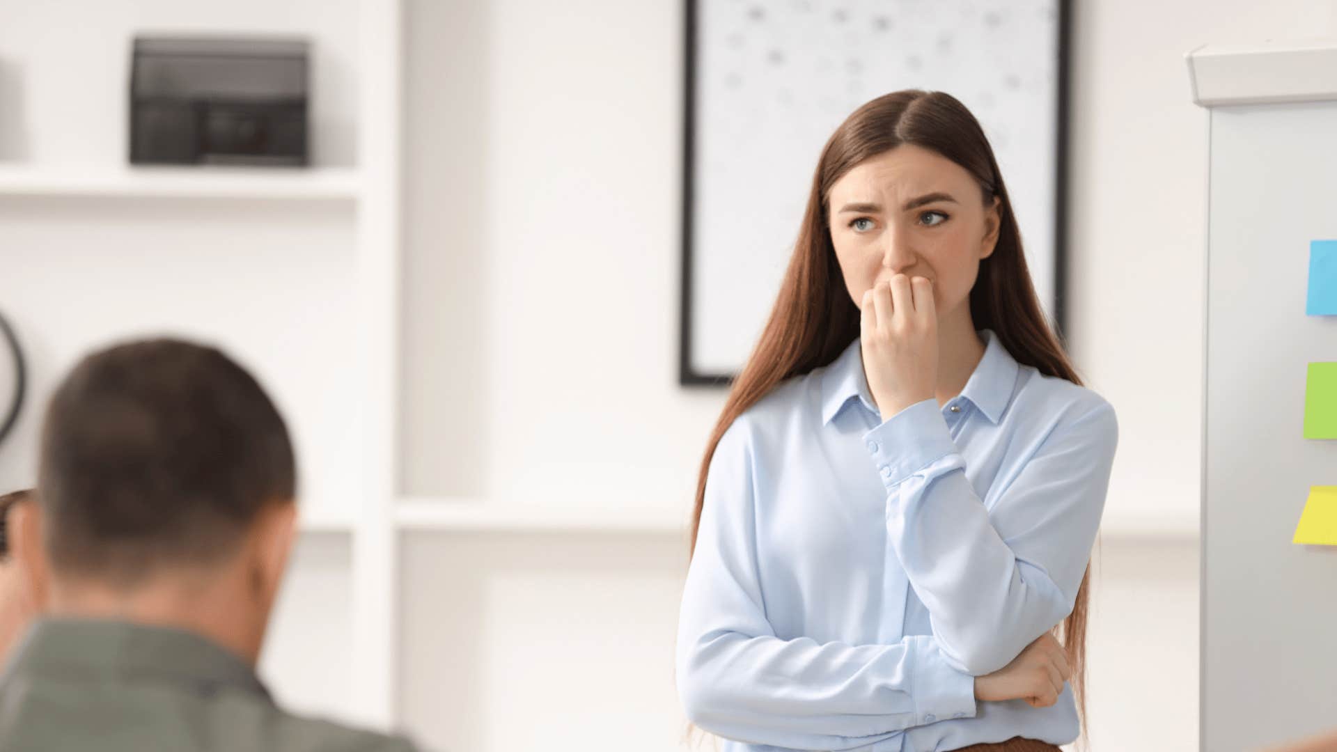 introverted woman biting her nails nervously at work