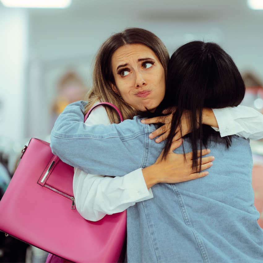 insecure woman reluctantly hugging friend in public