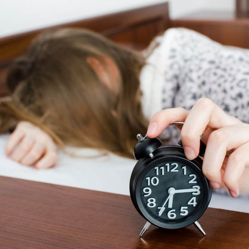 woman hitting her alarm clock waking up for work in the morning