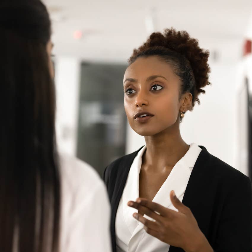 fake woman talking to colleague trying to get something from her