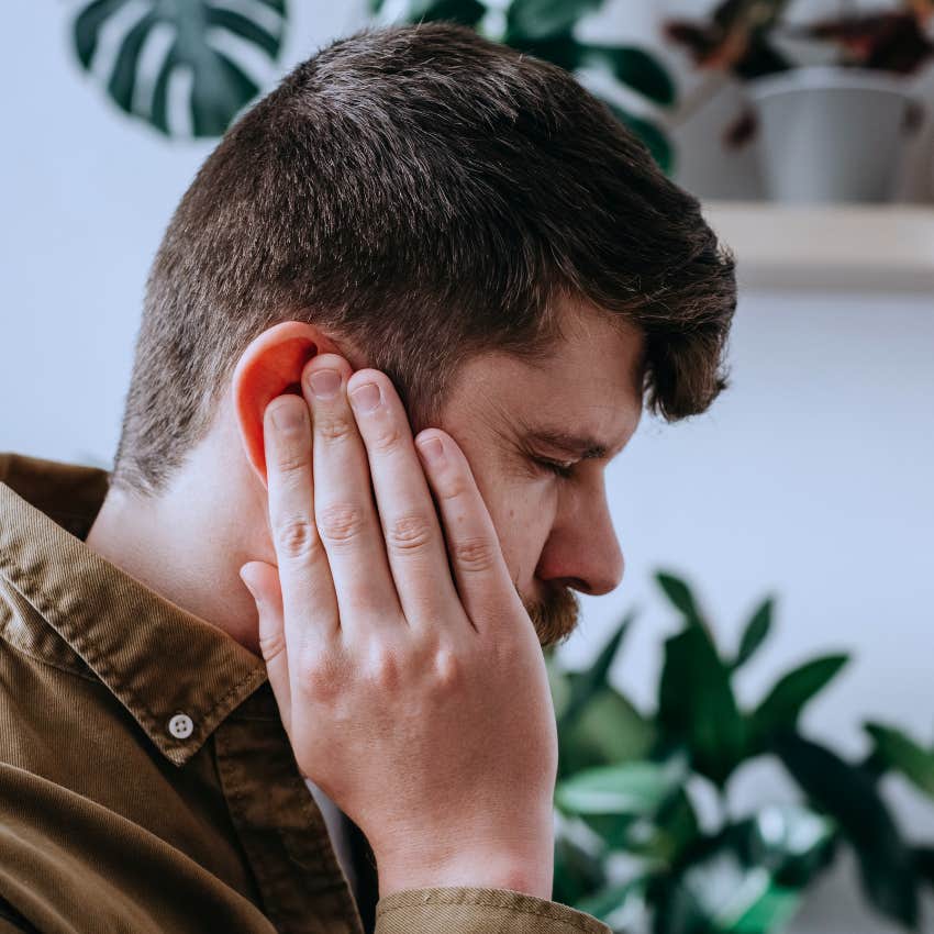 highly intelligent man covering his ears from loud chaos
