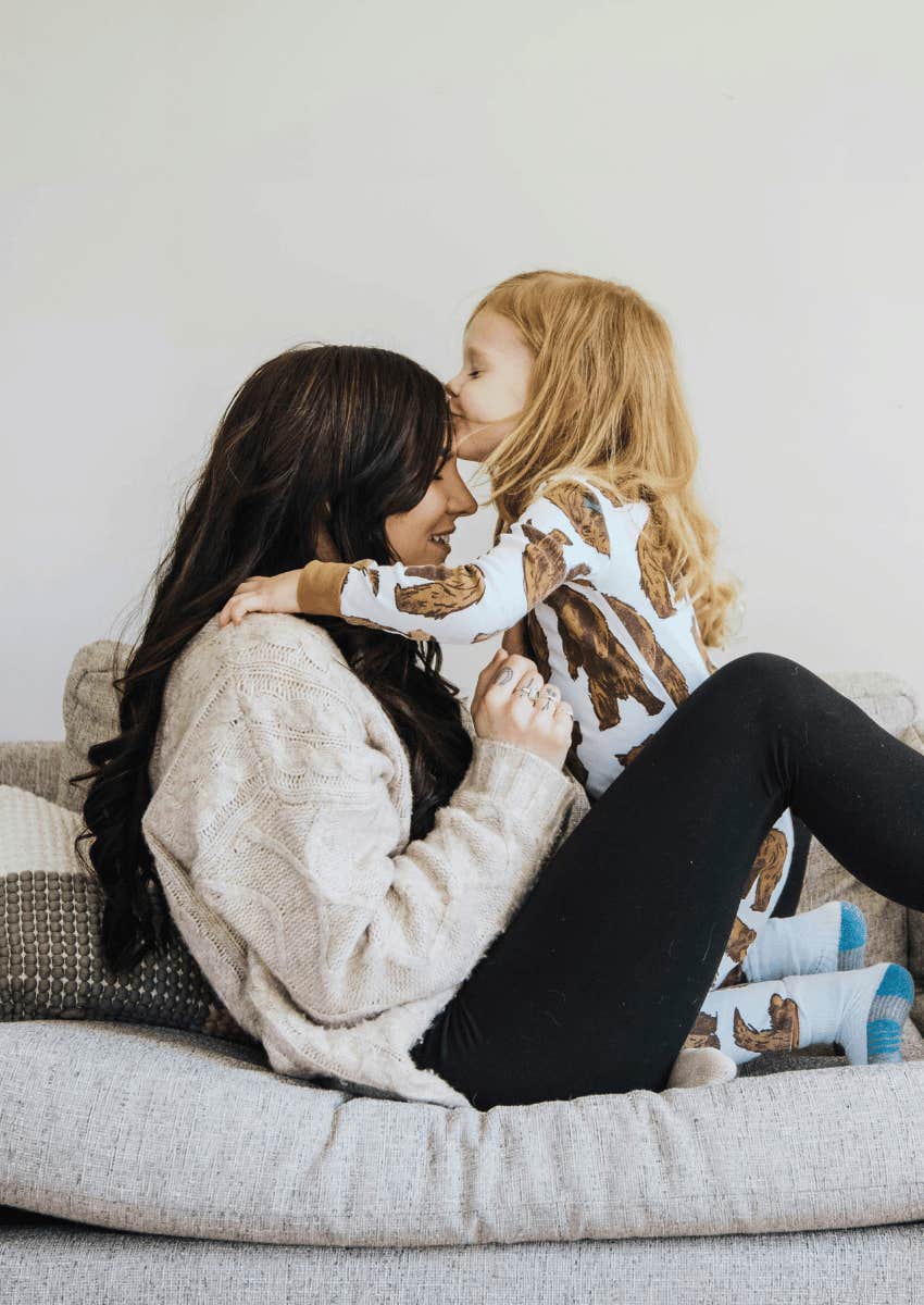 young girl kissing adult woman's forehead