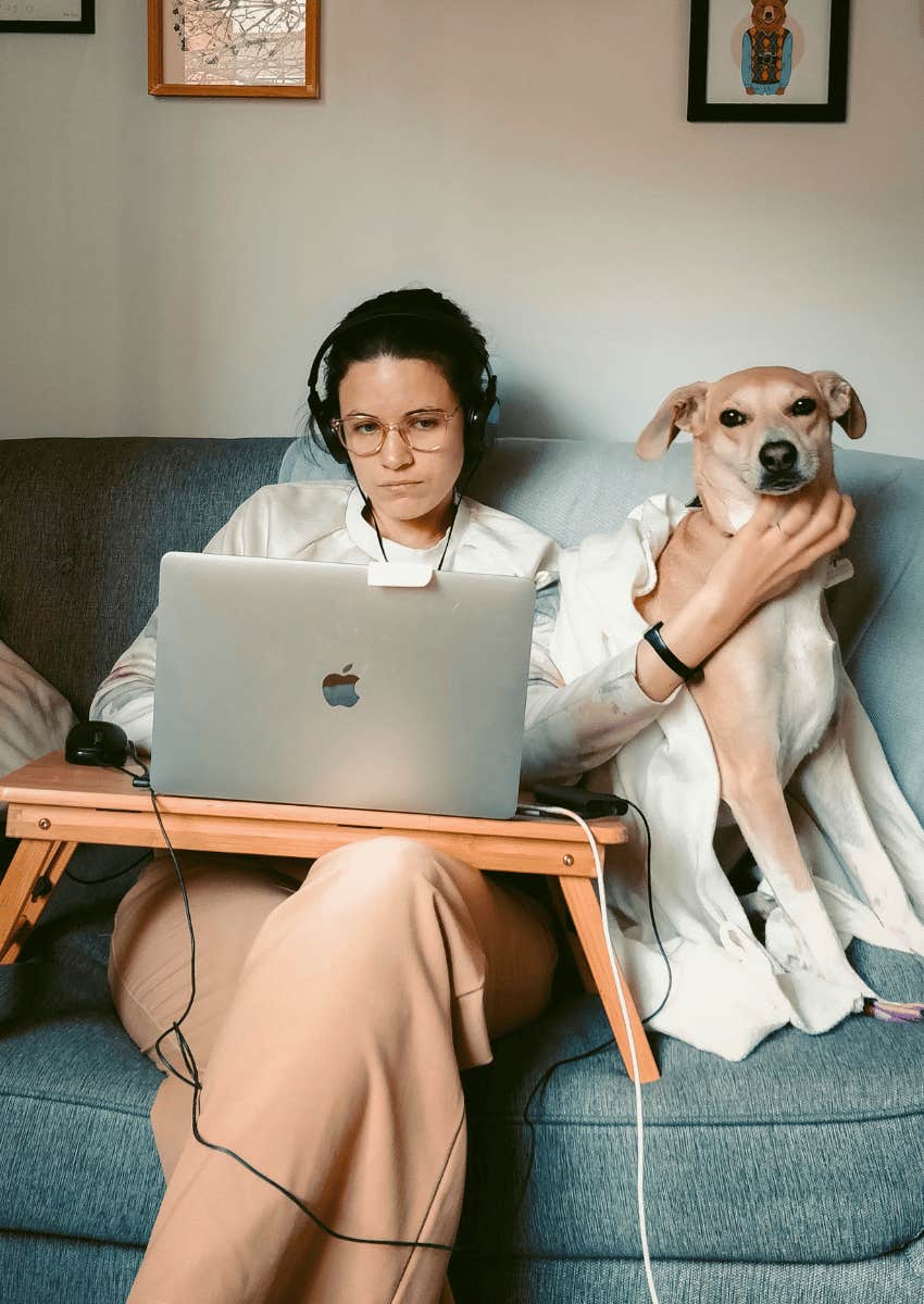 young woman working from home on a couch with her pet dog