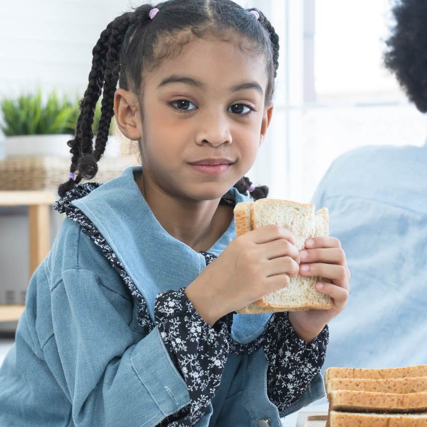 little girl eating a sandwich after learning how to cook from a young age
