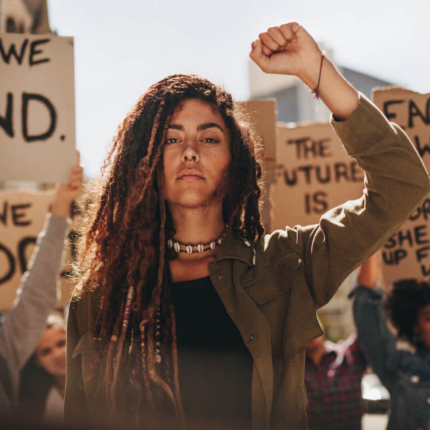 young woman activist holding up a fist to say power to the people