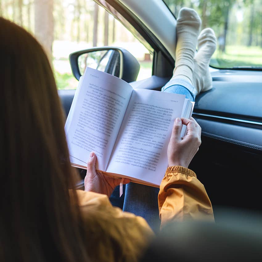woman reading book in her car