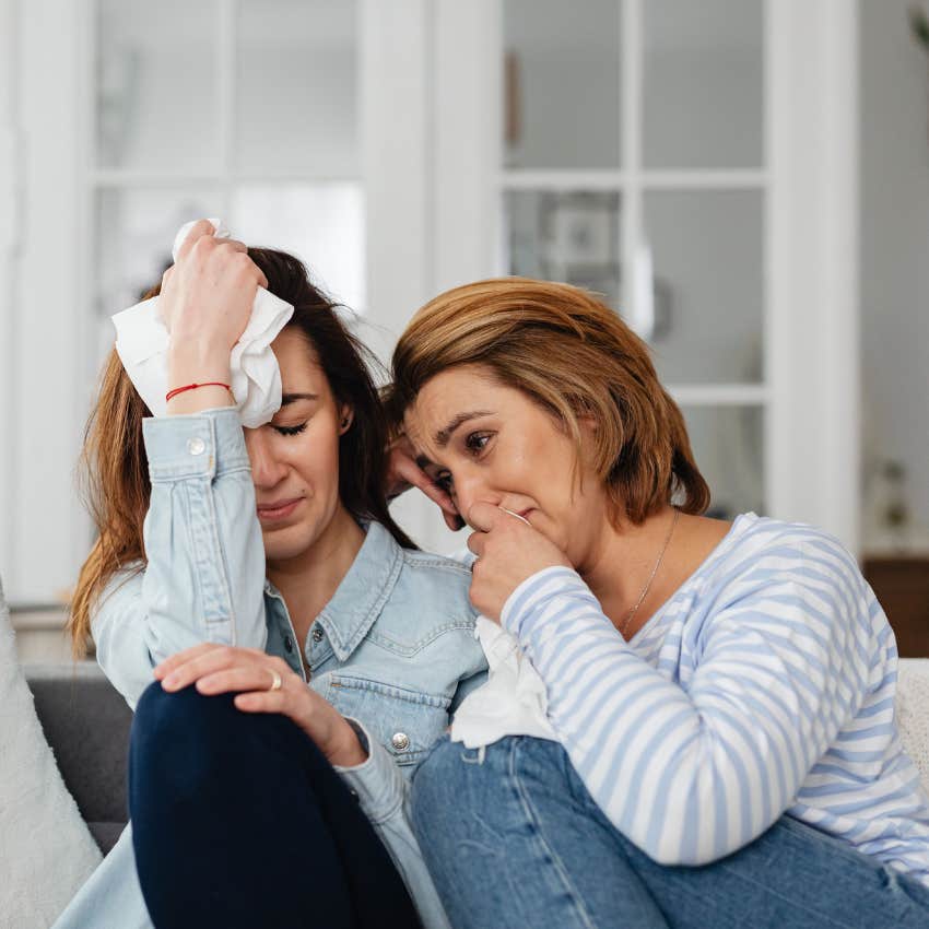 Thoughtful woman becoming emotionally overwhelmed while sitting beside a friend who appears emotionally overwhelmed also