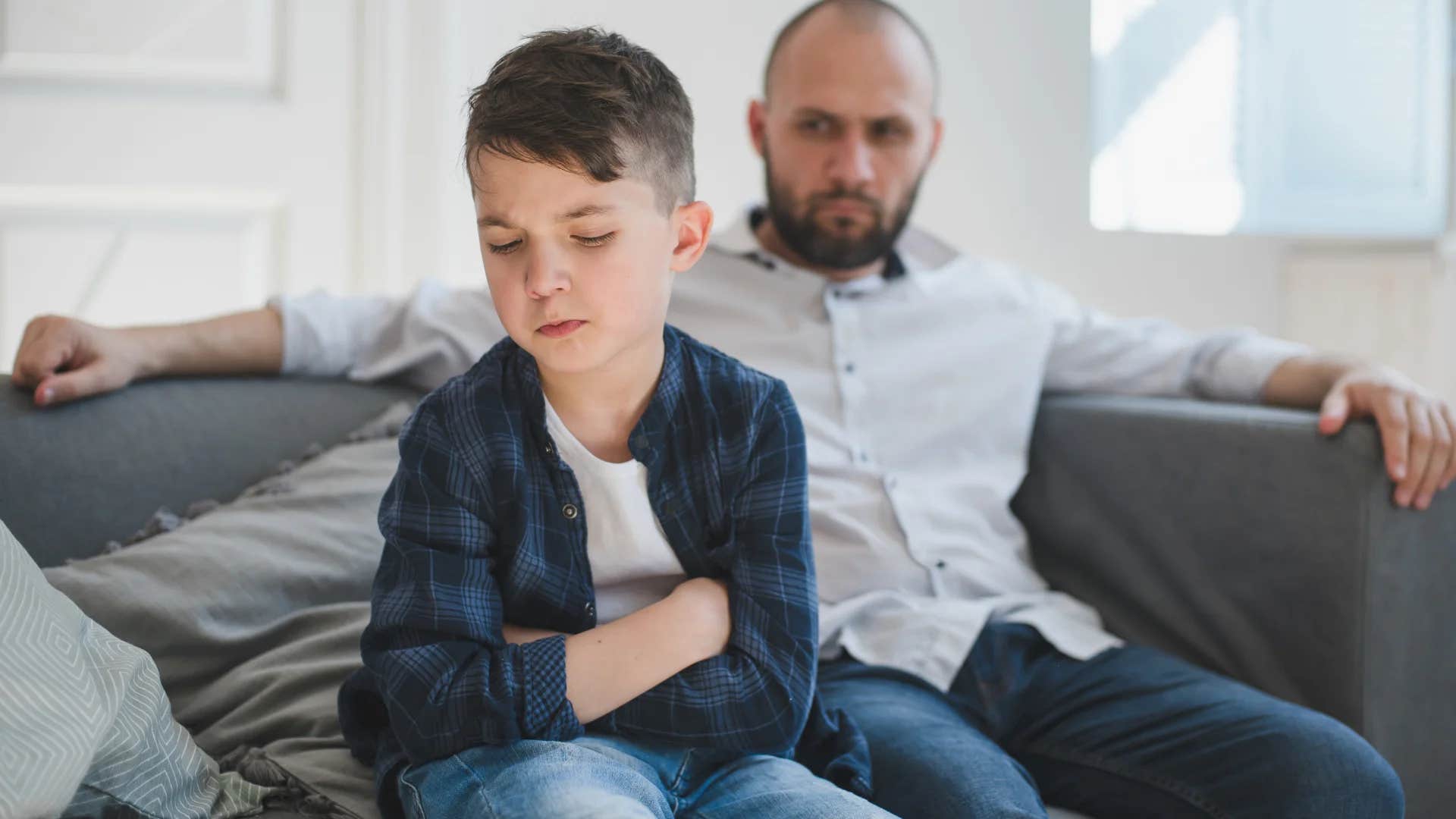 upset young boy turned away from dad who only offers conditional love