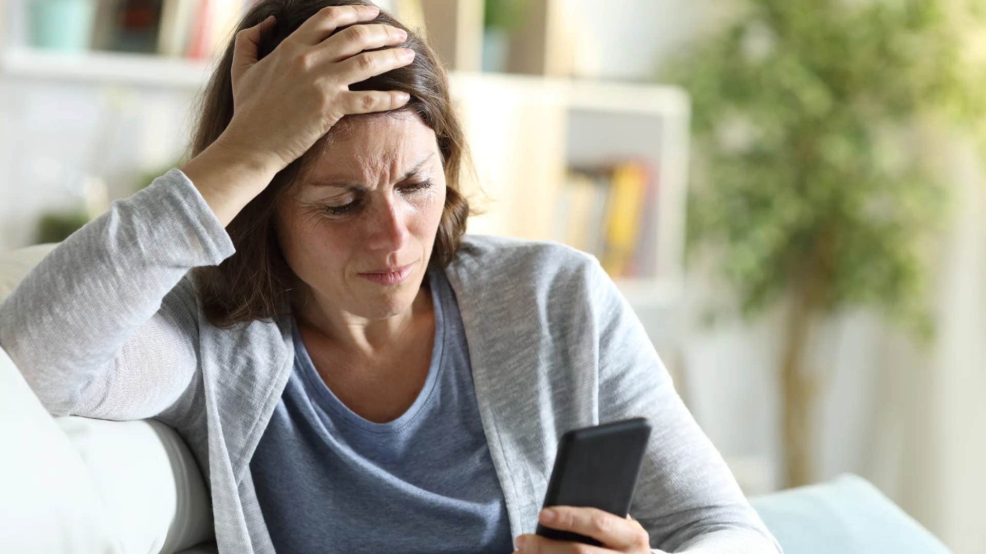 woman who feels unaccepted by her parents looking at phone stressed out