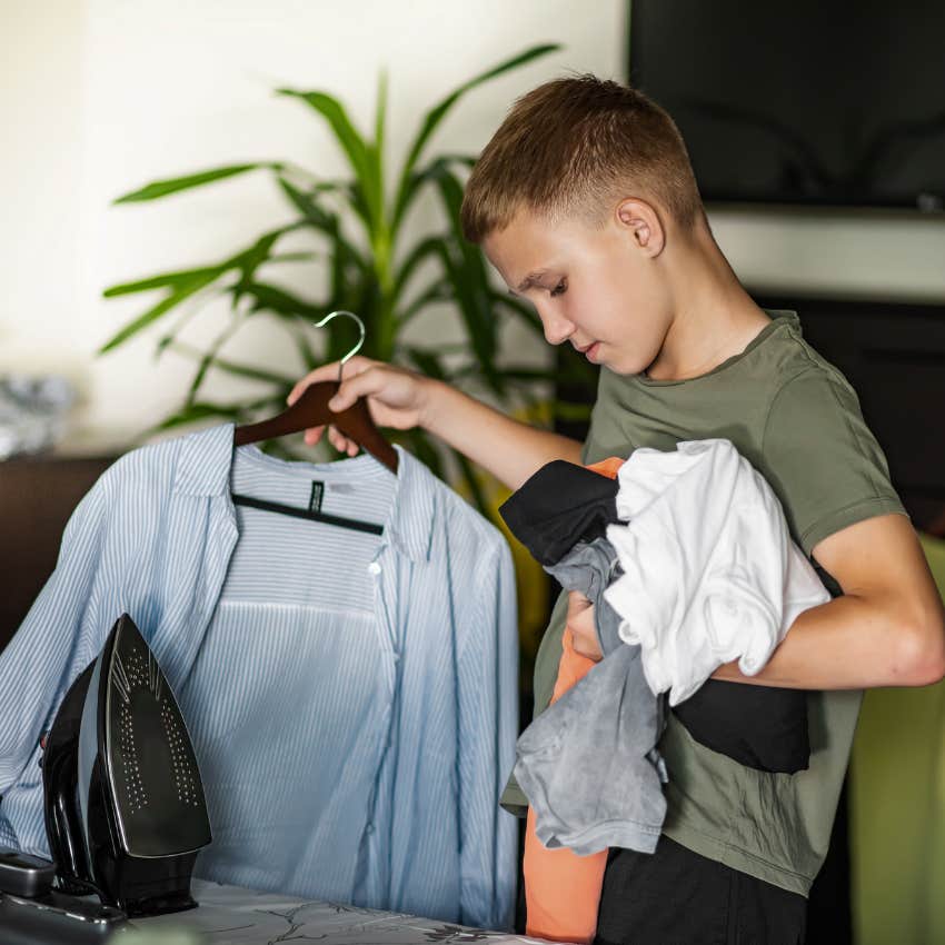 little boy holding clothes to iron them