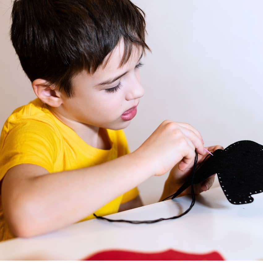 little boy sewing his own clothes at home