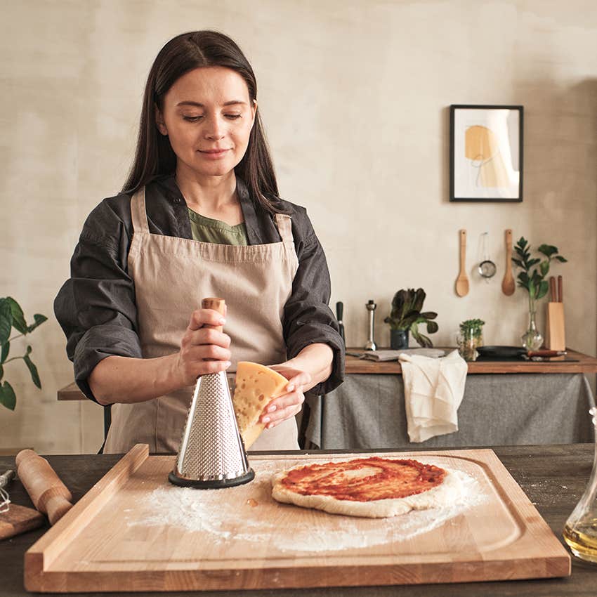 woman grating cheese for homemade pizza