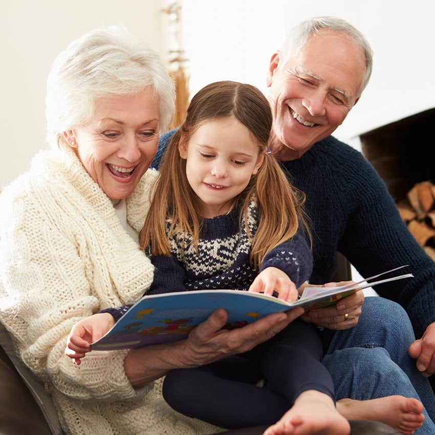 little girl spending time reading with grandparents