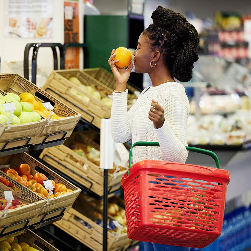 woman running errands alone smelling oranges