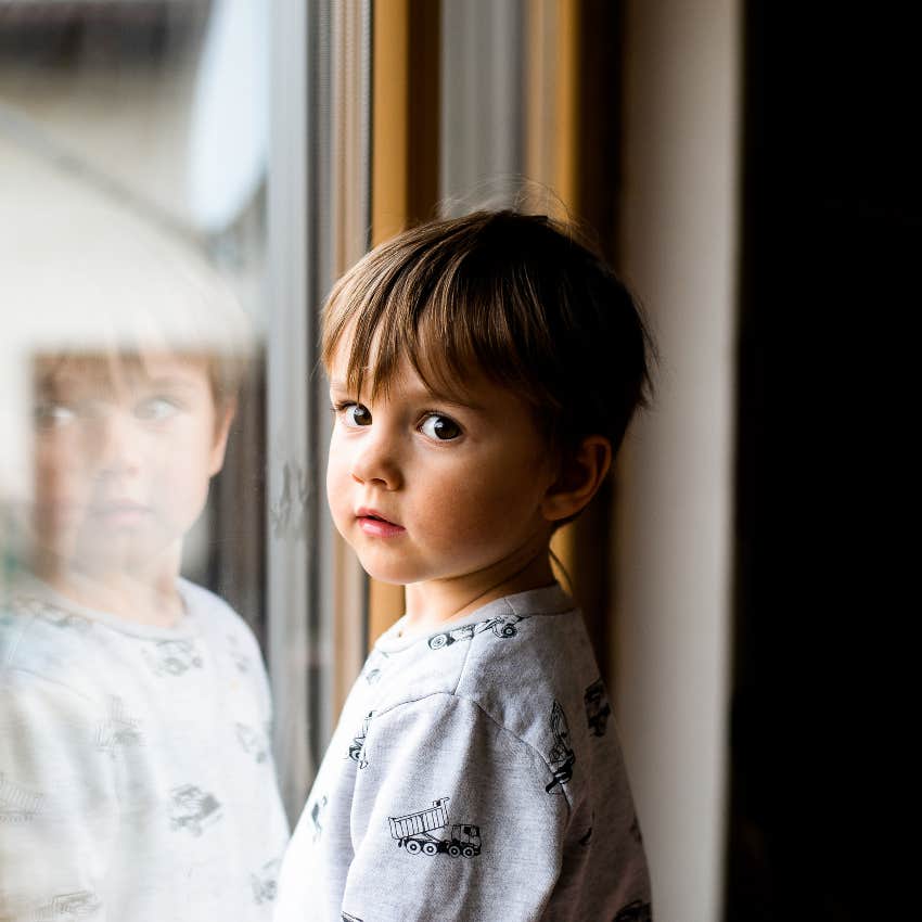sad little boy standing alone by the window