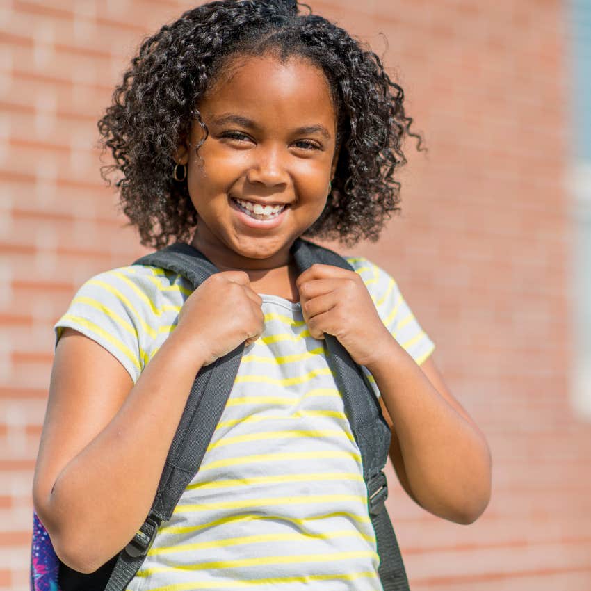 little girl with backpack standing alone to show she's independent 