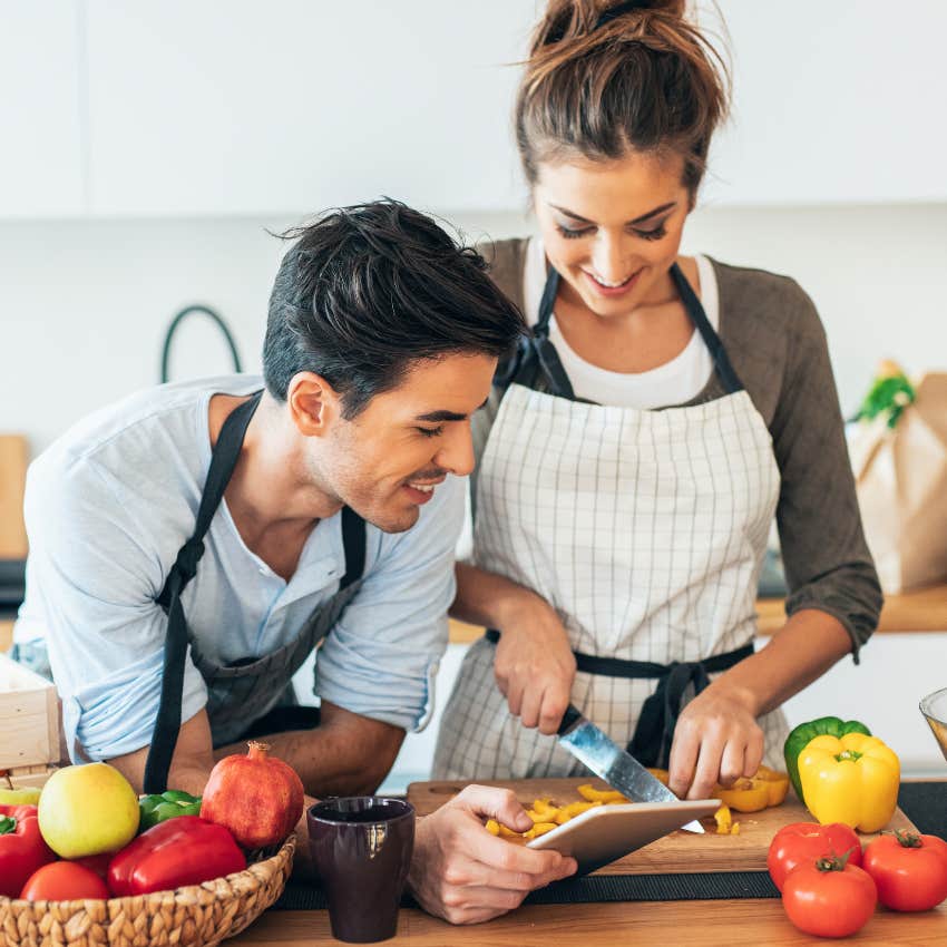 gen z couple happily cooking a meal from scratch in the kitchen