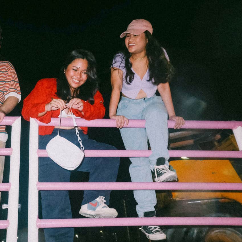 gen z women balancing on a fence