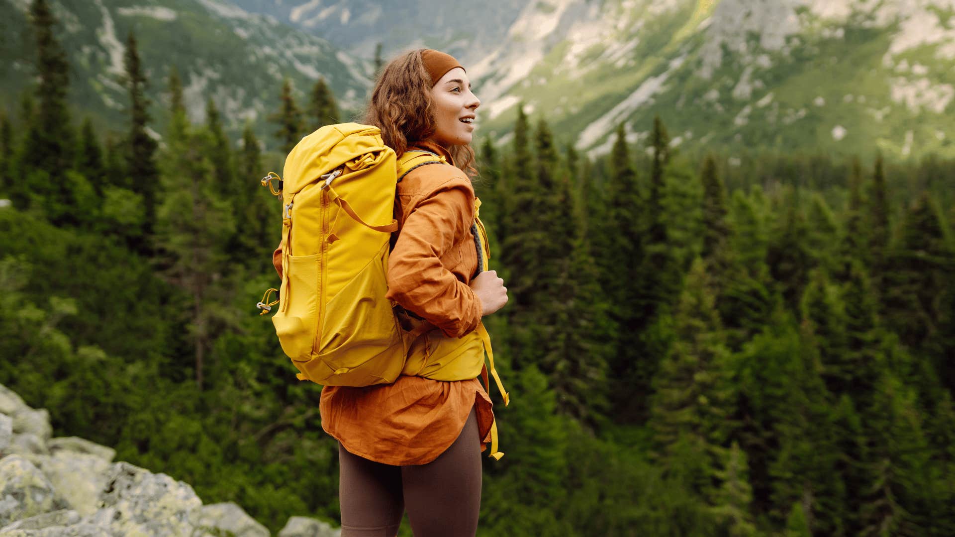 happy woman at the top of a mountain peak on a hike
