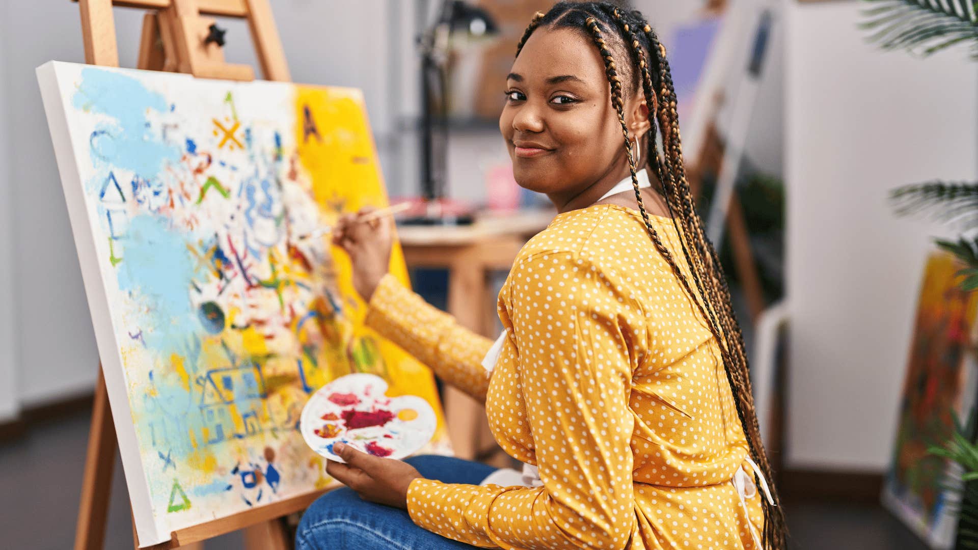 smiling talented woman painting a picture on canvas