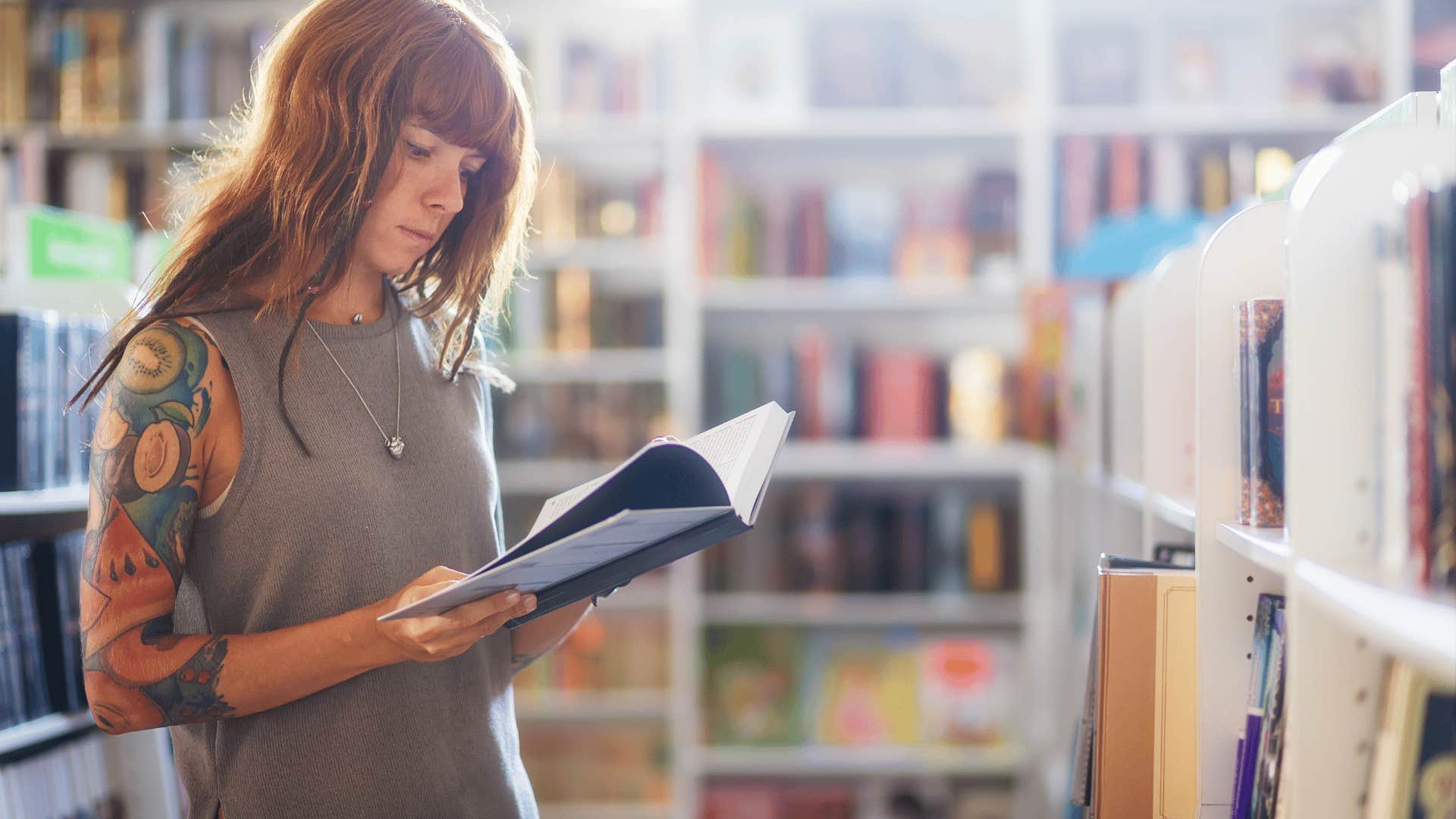 happy woman in the library reading multiple genres