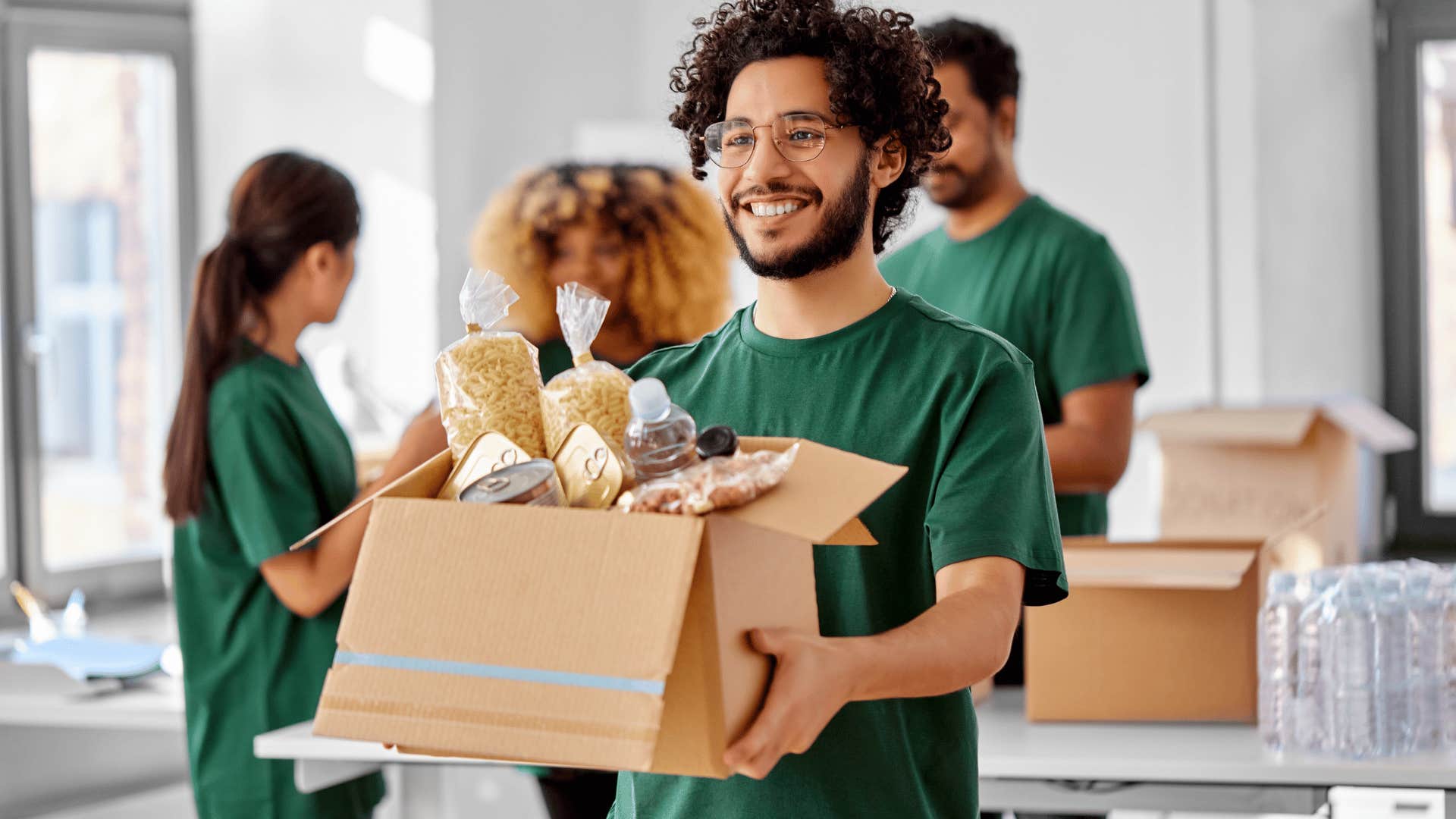 smiling man volunteering at a food pantry helping other people