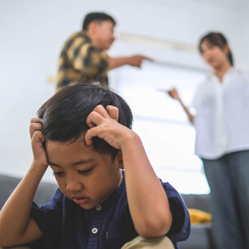 Little boy sitting alone with parents who argue constantly