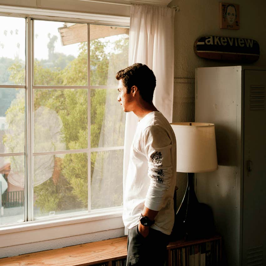 introvert man looking out of window ruminating
