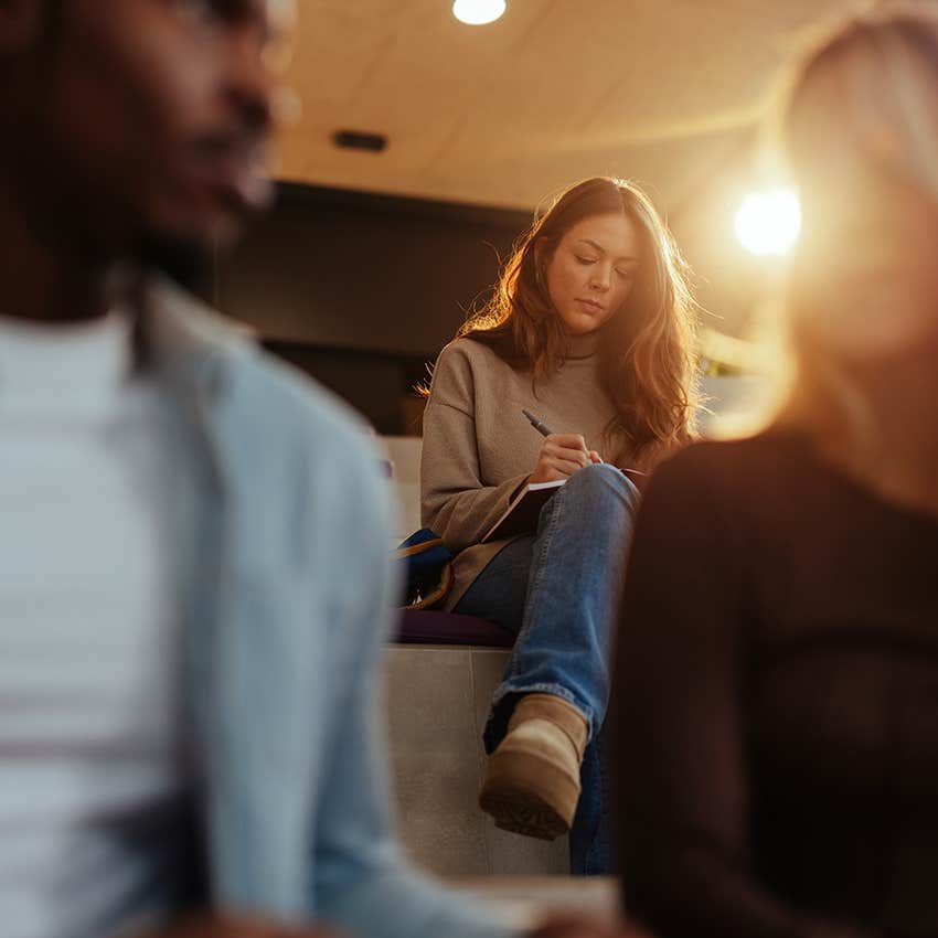 woman with a lone wolf personality sitting quietly in back of class taking notes