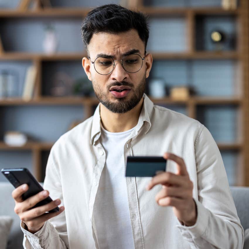 middle class man looking at credit card worried about money