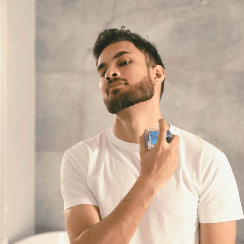 man applying cologne to his neck